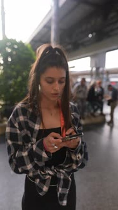 Junge Frau am Bahnhof nutzt Smartphone und spiegelt den modernen Lebensstil wider