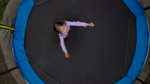Top View of a Jumping Girl From a Drone A Little Girl is Jumping on a Trampoline in the Yard The