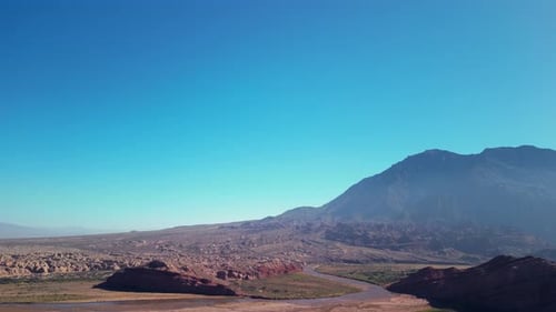 Aerial view drone flying over scenic rocky mountains landscape with a clear blue sky.