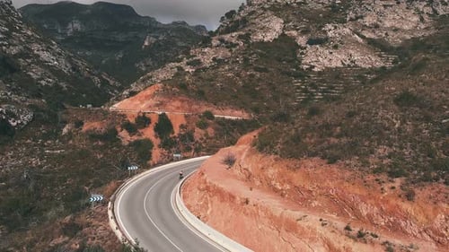 Cyclist Rides Winding Mountain Road on Cloudy Day