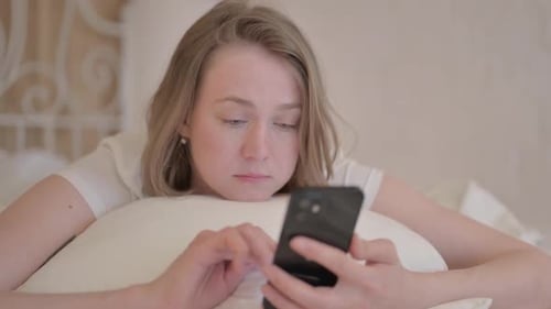 Woman Using Phone Lying in Bed at Home