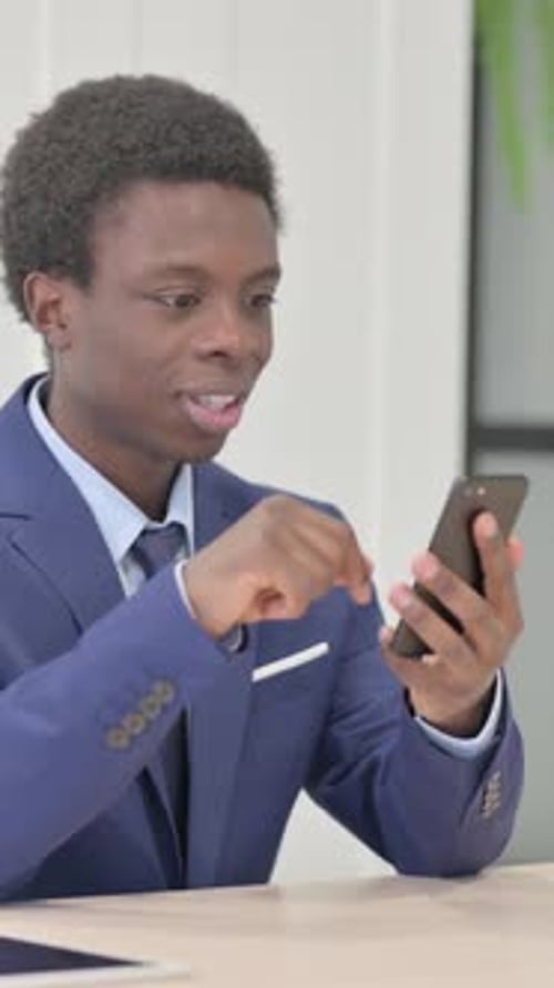 Excited Young Adult Man Using Smart Phone Indoors
