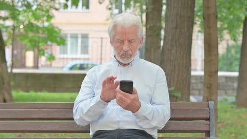 Senior Man Using Smartphone on Park Bench