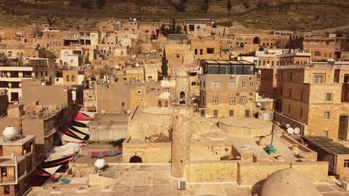 Aerial pull out view of historic stone city with domes and minaret in Mardin Turkey