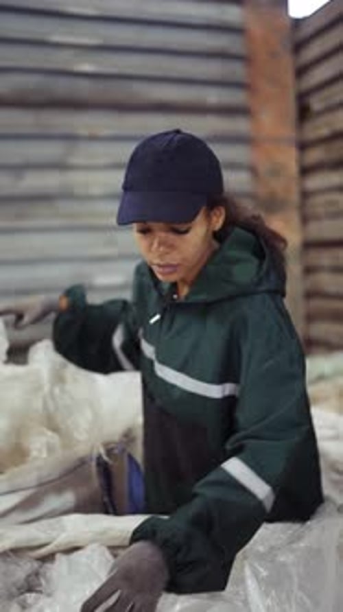 An AfricanAmerican Woman in a Special Uniform Sorts Polyethylene at a Waste Recycling Plant