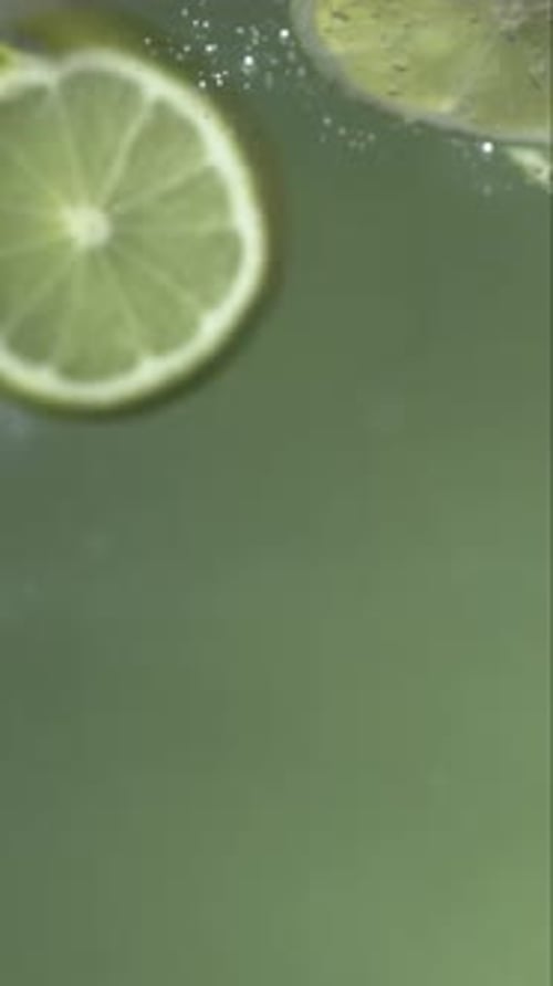 Lime Slices Falling into Water with Bubbles