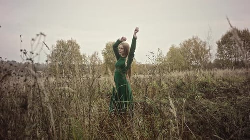 Model posing with arms raised in a field