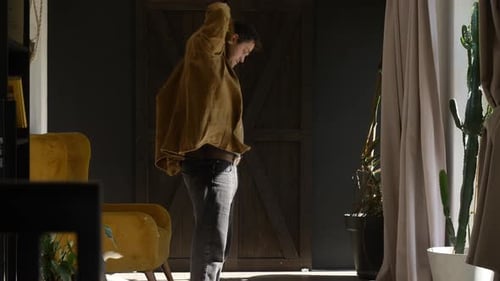man putting on a shirt at home during the day, video