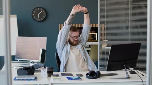 Young Man Stretching Himself At Work In Office
