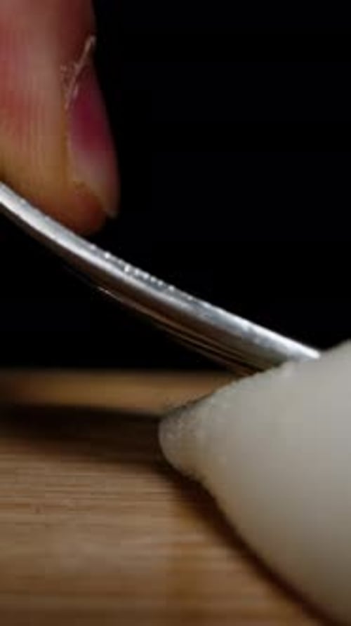 Vertical video. Boiled chicken eggs are crushed and mashed with a fork on a wooden table. Dolly