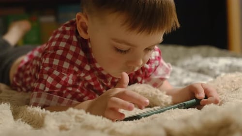 Boy Lying on Bed Using Smartphone