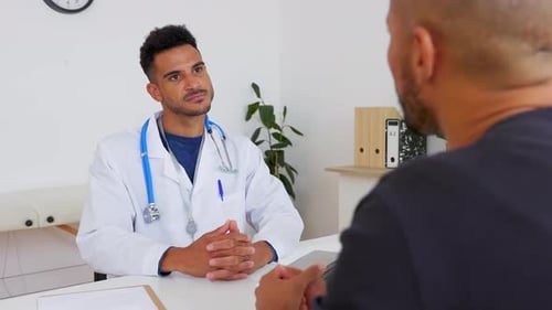 Doctor in Clinic Talking with Patient at Desk