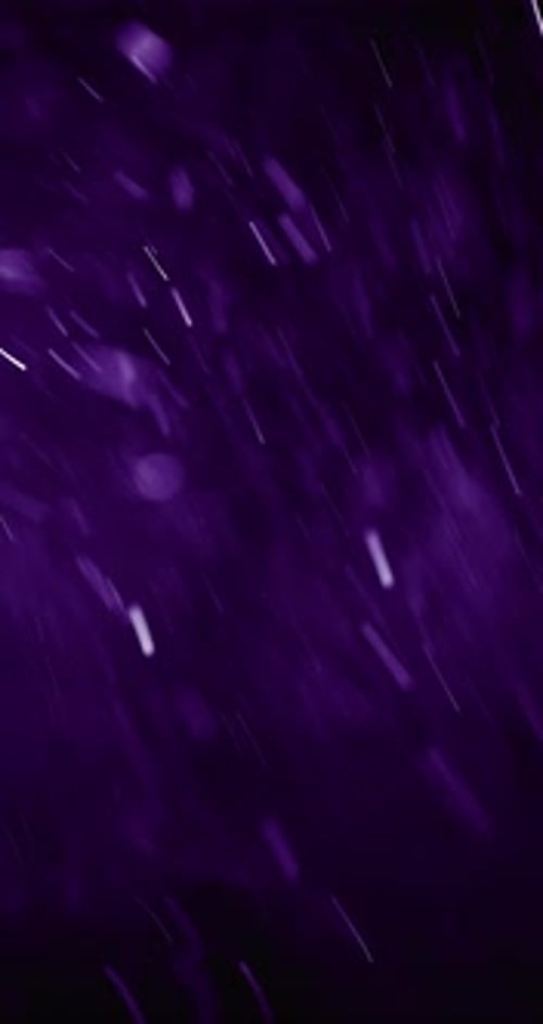 Weiße Partikel, die mit violettem Bokeh aufsteigen