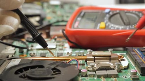 Technician Measuring Voltage on Laptop Motherboard During Electronic Diagnostics