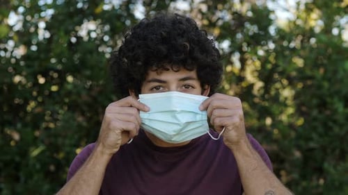 contagion, protection - young man at park wears mask staring at camera