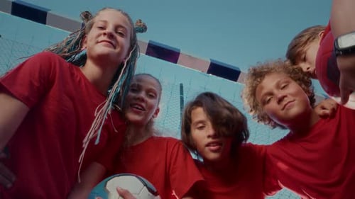 Young Football Players in Sports Uniforms Hug and Smile in Front of Football Goal