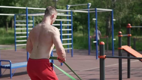 Shirtless Man Exercising Outdoors with Resistance Band