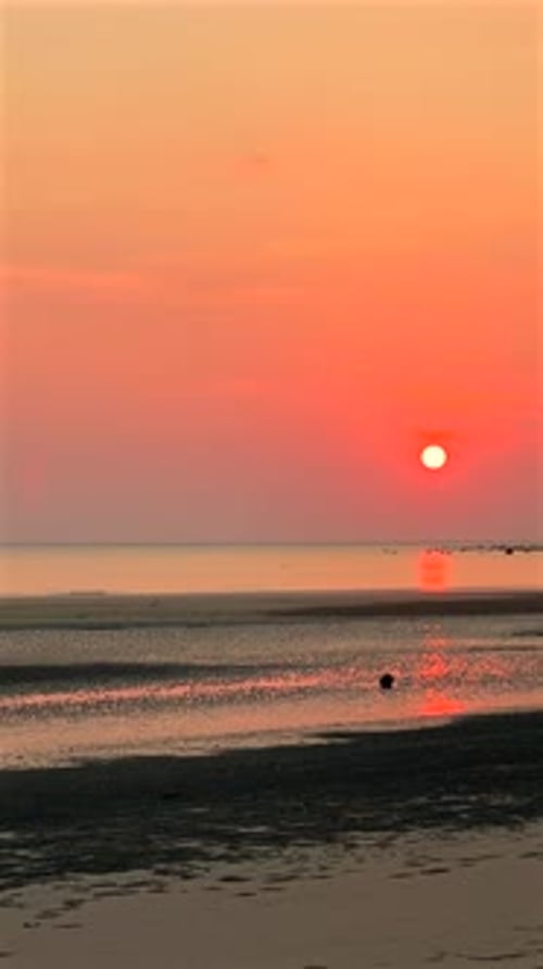 Serene Beach Landscape at Sunset with Tranquil Sea and Colorful Sky Reflecting on Water
