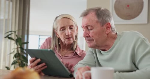 Senior Couple Using Tablet Device Together Indoors