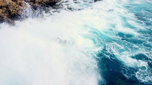 Sea Waves Washes the Rocky Shore Above Aerial Shot Flying Over Coastline Cliffside with Blue Pure