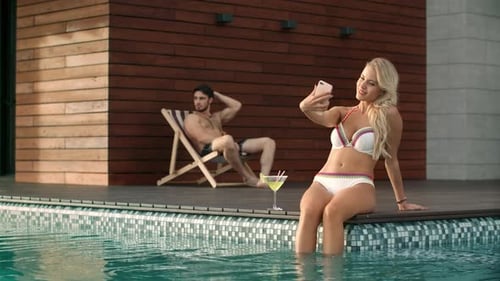 Sexy woman takes selfie photo in luxury resort pool during summer vacation