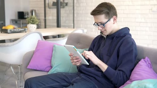 Teen Relaxing on Sofa Using Digital Tablet