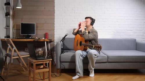 Young Man Feeling Overwhelmed and Frustrated Covering His Face with Hands While Sitting on a Couch