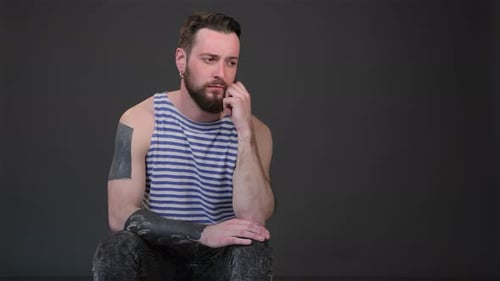 Contemplative Young Bearded Man in Striped Singlet