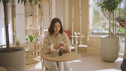 A Waiter Takes an Order From a Girl Who is Sitting at a Table in a Cafe A Beautiful Girl in a Good