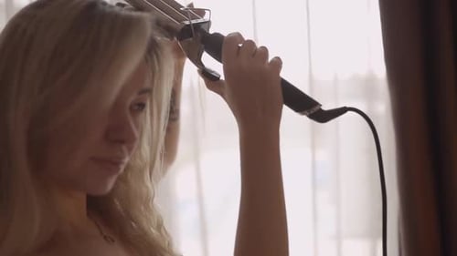 Blonde Woman Curls Hair with Curling Iron