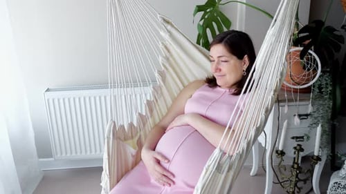 Pregnant Woman Relaxing in Hammock Chair Indoors