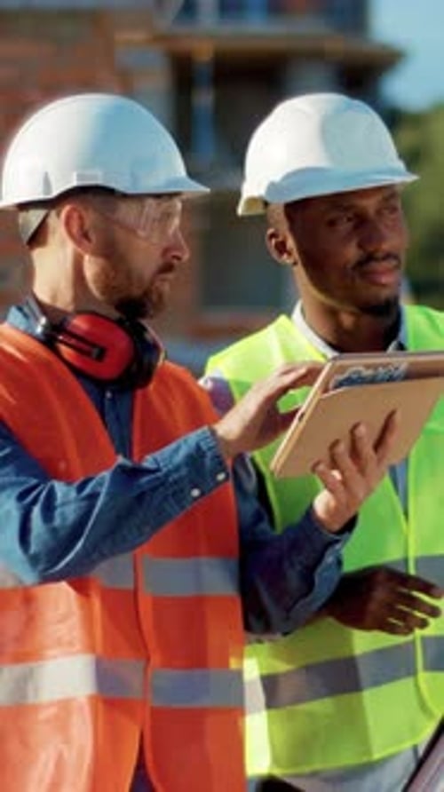 Construction Workers Reviewing Tablet on Building Site