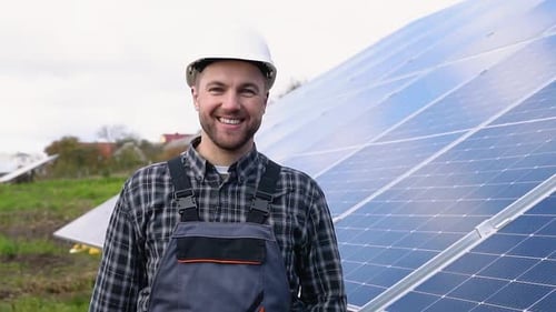 Male Engineer in Uniform Walking Through Solar Panel Field for Examination