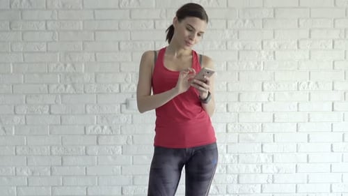 Woman in Active Wear Using Smartphone at Home