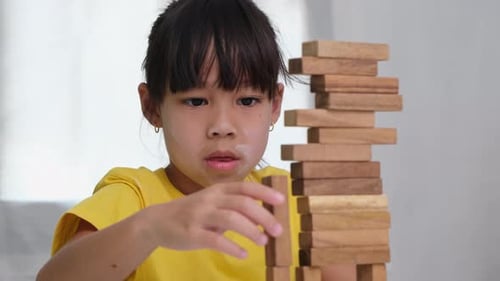 Asian cute little girl playing with constructor wooden block building.