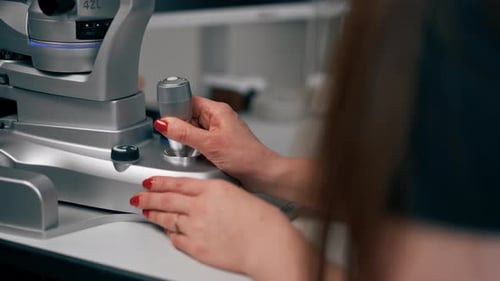 Close Up in an Ophthalmology Clinic Young Doctor Diagnoses a Young Girl with a Magnifying Lens