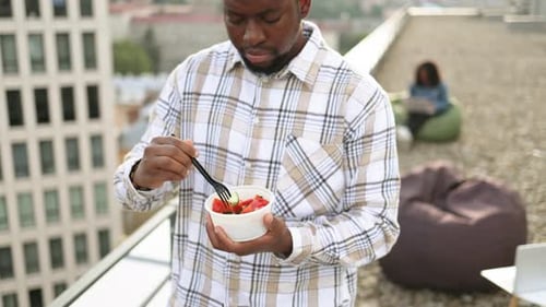 Man Eats Salad on Urban Rooftop