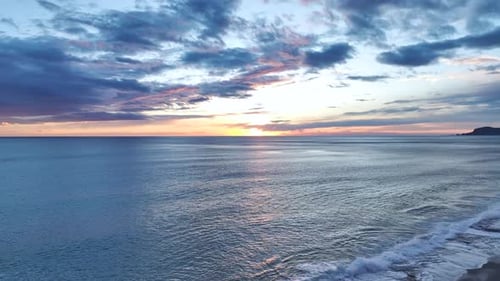 Aerial Video of Stunning Fiery Sunset With Purple Clouds Filling Sky Above Calm Blue Waters