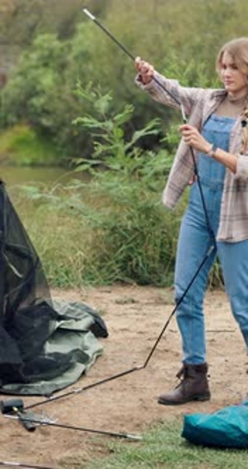Couple assembling tent near lake