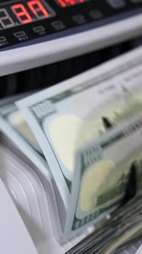 Electronic money counter machine is counting is counting the American hundred-dollar banknotes.