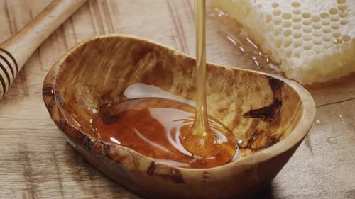 Honey Drips into Wooden Bowl with Honeycomb