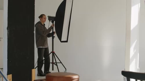 Photographer Assistant Adjusting Lighting Equipment in Studio