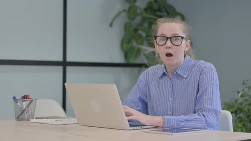 Woman reacts to computer screen in an office