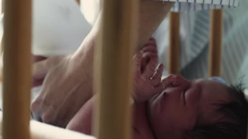 Infant Having Diaper Changed in Crib at Home