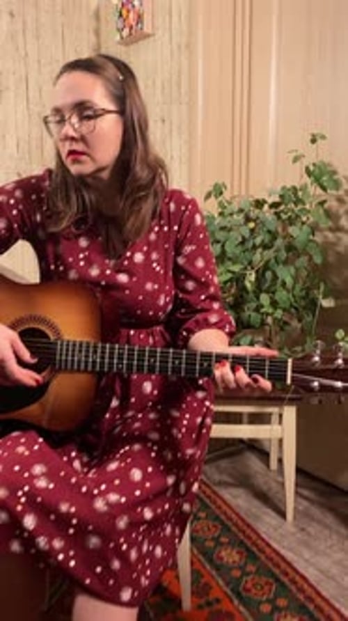 Woman Plays Guitar In Home Interior