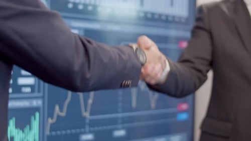 Businessmen Handshake Before Financial Screen