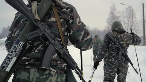 Camouflaged Soldiers Skiing Across Snow Covered Field