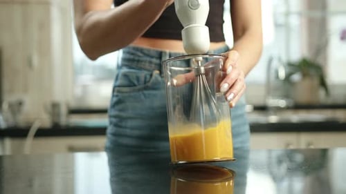 Woman Blending Sauce with Hand Blender in Kitchen