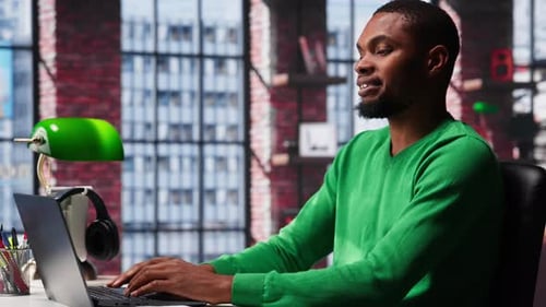 African American Male Teleworker Completing Spreadsheets on Laptop