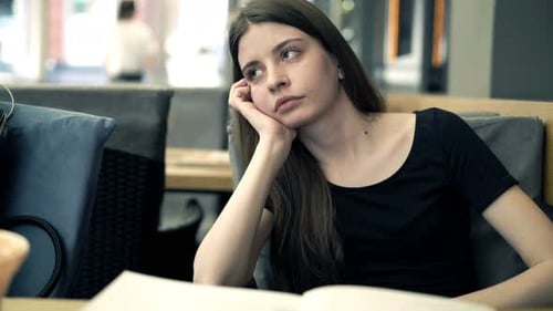 Young woman alone in blue cafe contemplating her troubles and worried thoughts